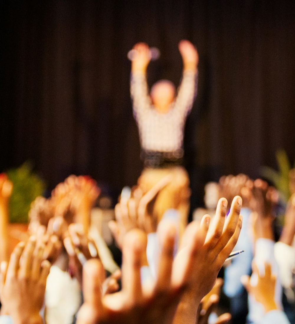 A crowd with raised hands cheering at a live event